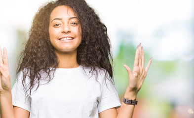 Young beautiful girl with curly hair wearing casual white t-shirt showing and pointing up with...