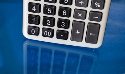 Part of the calculator on a blue, reflective background. Close-up.