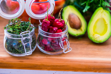 Close up of red hot chilly pepper on wooden table with mangos and other seasonal coloured fresh vegetables  home kitchen food scene