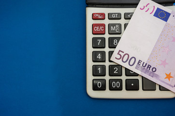 Obraz premium 500 euro banknote on a calculator, close-up, blue background