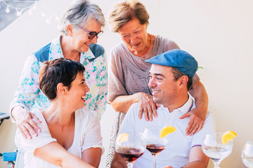 Family people cheerful portrait with mothers and son hugging and enjoying the friendship - mixed generations from old senior to adults together drinking red wine and cocktails
