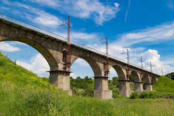 Beautiful old arched stone railway bridge against the backdrop of a scenic landscape