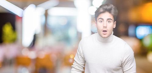 Fototapeta na wymiar Young handsome man wearing turtleneck sweater over isolated background afraid and shocked with surprise expression, fear and excited face.
