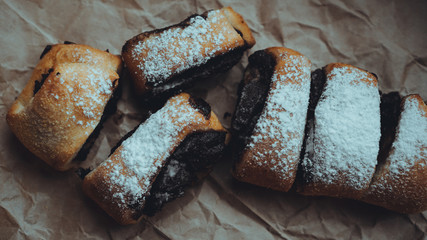 Freshly Baked Chocolate Rolls with a delicious filling, sprinkled with powdered sugar. Against the background of brown craft paper