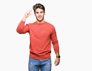Fototapeta premium Young handsome man over isolated background smiling and confident gesturing with hand doing size sign with fingers while looking and the camera. Measure concept.