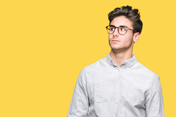 Young handsome man wearing glasses over isolated background smiling looking side and staring away thinking.