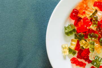 Close-up shot of mixed color gummy bears placed on a white plate with copy space – Sugary soft treats with fruit flavor – Funny shape chewie candies