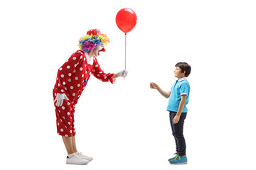Clown giving a red balloon to a boy