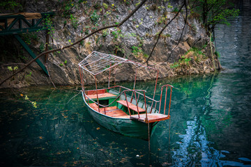 Landscape view of a green metal boat on colourful water. Canyon Matka, north Macedonia.