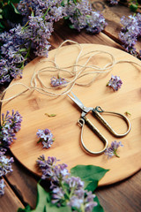 scissors and lilac on wooden background top view