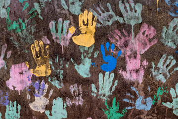 Dark background with colorful handprints symbolising interracial friendship
