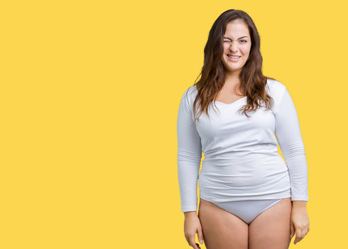 Beautiful plus size young overwight woman wearing white underwear over isolated background winking looking at the camera with sexy expression, cheerful and happy face.