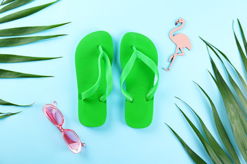 Green palm leaves with accessories and clothing items or summer symbols, beachwear on colored paper...
