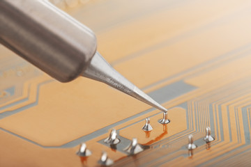 Soldering of electronic circuit board with electronic components. Soldering station. Engineers repair circuit board with soldering iron.