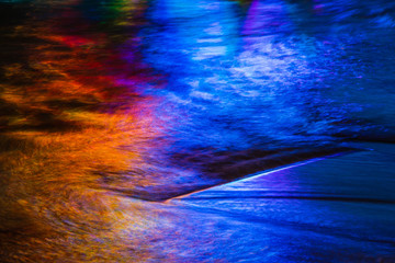 Warm and cool colors mixing and reflecting on the surface of water with small waves and ripples.