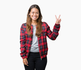 Young beautiful brunette woman wearing a jacket over isolated background smiling with happy face winking at the camera doing victory sign. Number two.