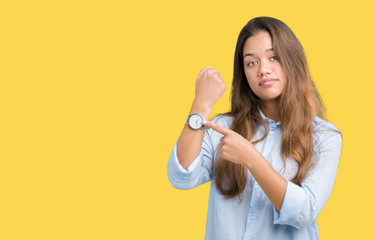 Young beautiful brunette business woman over isolated background In hurry pointing to watch time,...