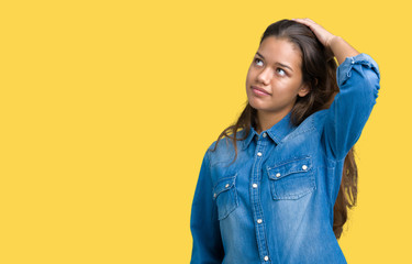 Young beautiful brunette woman wearing blue denim shirt over isolated background Smiling confident touching hair with hand up gesture, posing attractive