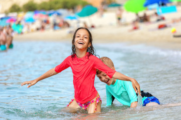 Happy children having fun at beach playing in water during summer vacation