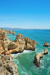 Rocky beaches with cliffs somwhere, somwhere in Algarve, Portugal. Atlantic ocean shore background. Copy space for text.