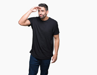 Fototapeta premium Young handsome man over isolated background very happy and smiling looking far away with hand over head. Searching concept.