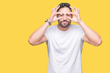 Fototapeta premium Handsome man wearing white t-shirt over yellow isolated background Trying to open eyes with fingers, sleepy and tired for morning fatigue