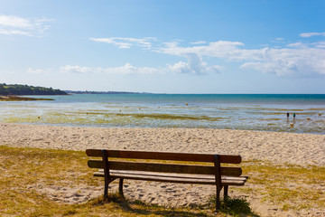 Naklejka na ściany i meble Bench with a view of a beautiful beach in Kerleven, Brittany, France, on a sunny day