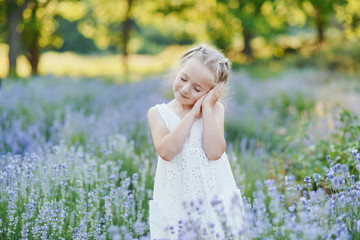 Little girl in lavender field. kids fantasy. Smiling girl sniffing flowers in summer purple lavender field.