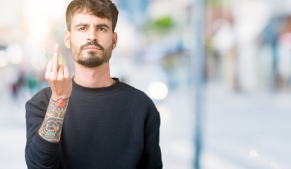 Young handsome man over isolated background Showing middle finger, impolite and rude fuck off expression