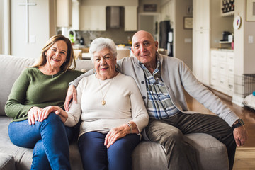 Portrait of multigenerational family sitting on living room couch