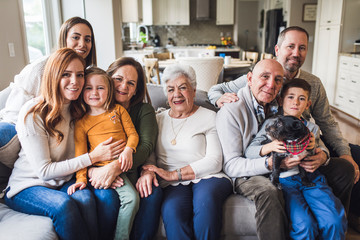 Portrait of multigenerational family sitting on living room couch