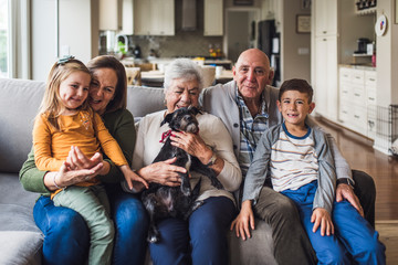 Portrait of multigenerational family sitting on living room couch