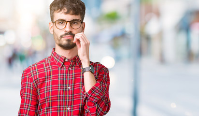 Young handsome man wearing glasses over isolated background mouth and lips shut as zip with...