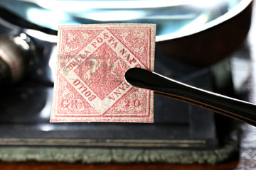 Postal forgery of the 1858 Kingdom of Naples 20 Grana stamp held by tweezers. 