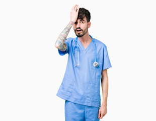 Young handsome nurse man wearing surgeon uniform over isolated background surprised with hand on...