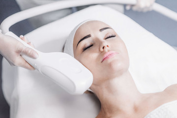 beautician makes the girl a laser procedure on the face