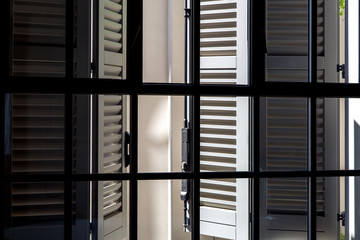 gray wooden shutters on a sunny day view from the inside through a window with a black frame and...