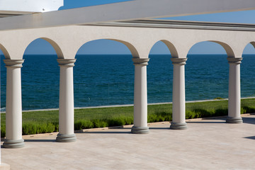an arch with columns of white stone and a marble floor on sunny day of a luxurious mansion, nobody.