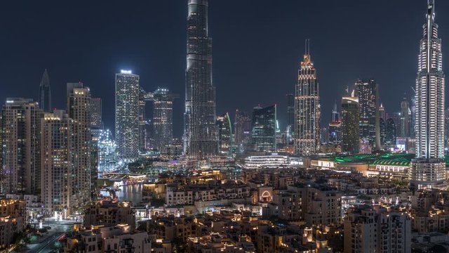 Dubai Downtown skyline night timelapse with Burj Khalifa and other towers paniramic view from the top in Dubai, United Arab Emirates. Traffic on circle road and fountains. Traditional and modern