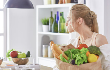 Young woman holding grocery shopping bag with vegetables Standing in the kitchen