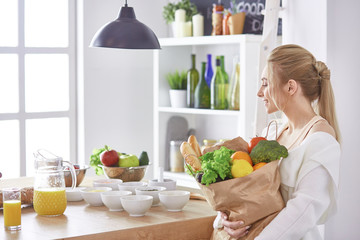 Young woman holding grocery shopping bag with vegetables Standing in the kitchen