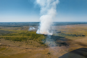 Fototapeta na wymiar Forest fire in hot summer day, burning dry grass and trees on field, aerial view