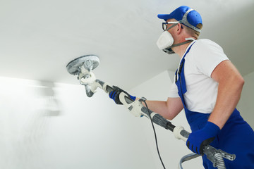 Painter work with ceiling. polishing and sanding the surface after putty for painting