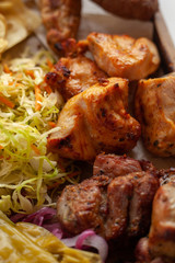 Macro close up of assorted grilled meat snacks: chicken, beef and lamb kebab, roasted pork shish kebab, served with coleslaw