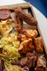 Macro close up of assorted grilled meat snacks: chicken, beef and lamb kebab, roasted pork shish kebab, served with coleslaw