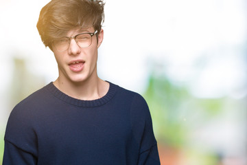 Young handsome man wearing glasses over isolated background winking looking at the camera with sexy expression, cheerful and happy face.