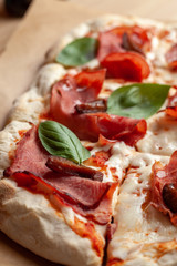 Macro close up of roman square pizza on a thick dough with mozzarella, pastrami, sweet plum and basil leaves, served on a wooden table