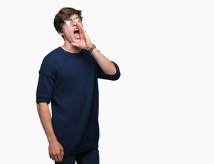 Young handsome man wearing glasses over isolated background shouting and screaming loud to side with hand on mouth. Communication concept.