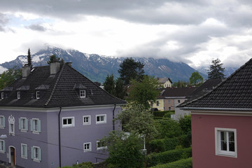 Fototapeta na wymiar Beautiful landscape with neat town houses and high inaccessible snow alps mountains at far in the clouds in overcast day