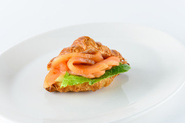 Freshly baked french croissant with cream cheese, green leaves and smoked salmon, isolated on white